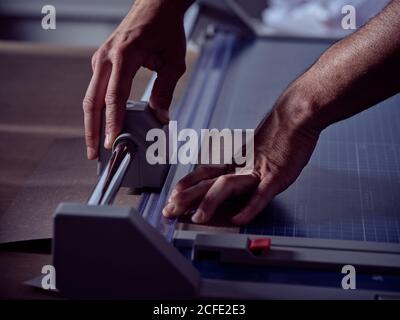 Crop Hände des Handwerkers Messung Blatt Pappe mit professionellen Rollfräser Stockfoto