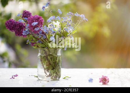 Frühling oder Sommer Hintergrund. Ein Bündel von hellen Blumen in einem Glas von Sonnenlicht beleuchtet. Schöne Blumen auf grünem Hintergrund. Stockfoto