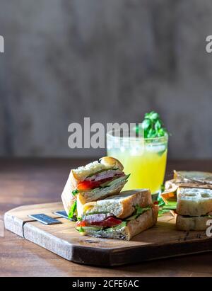 Ciabatta Sandwich mit truthahn, Salat, Tomaten, Käse auf einem Holzbrett. Stockfoto