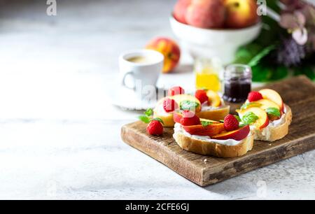 Summer Snack: Sandwiches mit Frischkäse und frischen Pfirsichen auf hellem Betonboden. Hausgemachtes Sommerfrühstück. Stockfoto