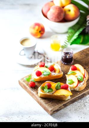 Summer Snack: Sandwiches mit Frischkäse und frischen Pfirsichen auf hellem Betonboden. Hausgemachtes Sommerfrühstück. Stockfoto