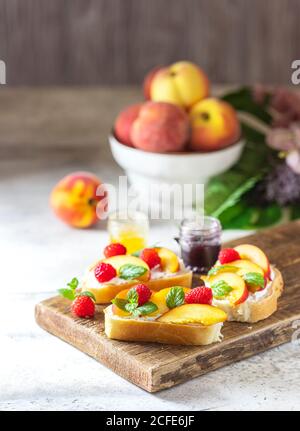 Summer Snack: Sandwiches mit Frischkäse und frischen Pfirsichen auf hellem Betonboden. Hausgemachtes Sommerfrühstück. Stockfoto