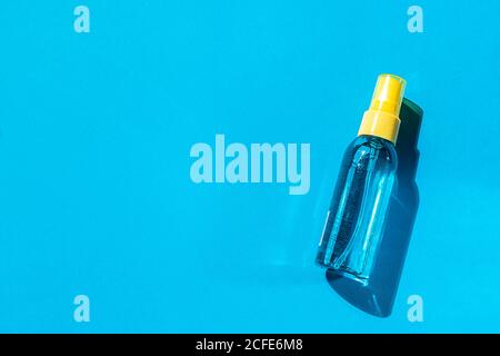 Kosmetische Sprühflasche blau und gelb mit transparenter Flüssigkeit auf blauem Hintergrund. Wellness-Kosmetik. Natürliche Hautpflege. Stockfoto