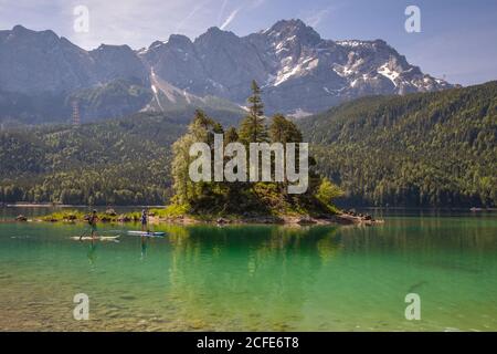 Zwei Stand-up-Paddler vor der Insel Schönbichl (Schönbühl, Schönbüchel) am Eibsee mit Blick auf die Zugspitze, türkis (grün) Stockfoto