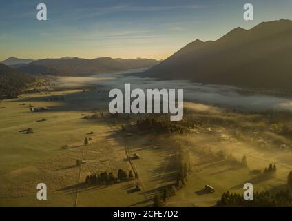 Krün im Herbstnebel, Luftbild mit Blick über das Isartal, rechts das Soierngebirge, Bauernstadel, blauer Himmel, Stockfoto