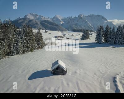 Bauernstadel im Winter in Mittenwald gegen Karwendelgebirge, schneebedeckte Bäume, Mittenwald, blauer Himmel, Garmisch-Partenkirchen, Oberbayern, Stockfoto