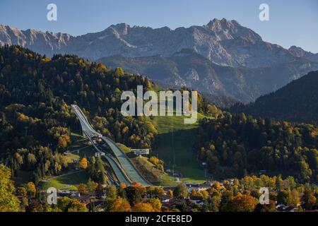 Große Olympia-Schanze in Garmisch-Partenkirchen im Herbst gegen Gudiberg und Partenkirchner Dreiterspitze im Wettersteingebirge, blauer Himmel, Stockfoto