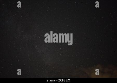 Milchstraße und viele Sterne vor einem schwarz blauen Nachthimmel, orange gefärbte Wolke im Vordergrund. Deutschland. Stockfoto