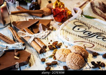 Cinammon-Sticks mit Juteseil, Kaffeekanne, Süßigkeiten und Keksen auf weißem Holzhintergrund gebunden. Kaffeepause oder Frühstück im Hintergrund. Stockfoto