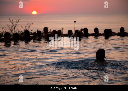 Junge Frau schwimmt im Infinity-Pool, Pool-Party, Sonnenuntergang, Sonne, Silhouette, Meer, junge Frauen, junge Männer, Mittelamerika, Costa Rica Stockfoto