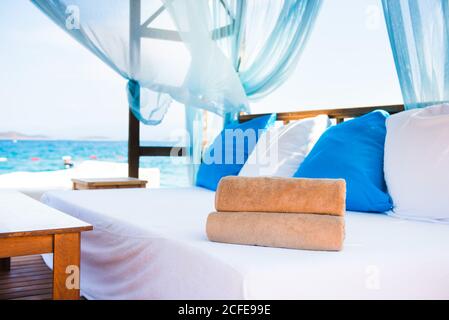 Set von gerollten Strandhandtüchern, die auf einer weißen Couch liegen In einem Luxus-Hotel Cabana in der Nähe des Meeres Stockfoto