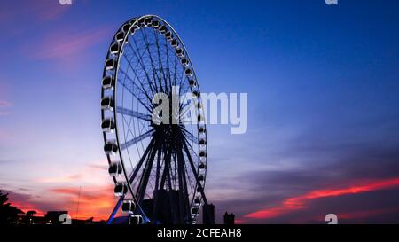 Teil von Riesenrad in Bewegung gegen einen blauen Himmel Hintergrund mit Lichtern von Nachtbeleuchtung nach Sonnenuntergang Zeit. riesenrad Hintergrund für Tapete Stockfoto