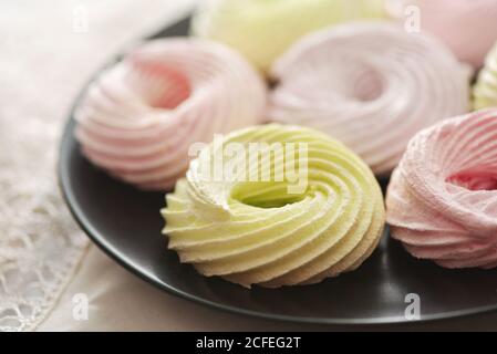 Nahaufnahme von frischen Baiser-Ringen auf schwarzem Teller Stockfoto