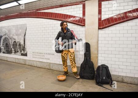 LONDON, ENGLAND - 06. APRIL 2017: Innenansicht einer U-Bahn-Station mit Bildern an den Wänden und Straßenmusikanten. Stockfoto