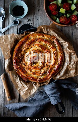 Von oben Ernte kochen hält heißen Auflaufform mit frisch Blätterteig und Servierstück borek auf Teller Stockfoto