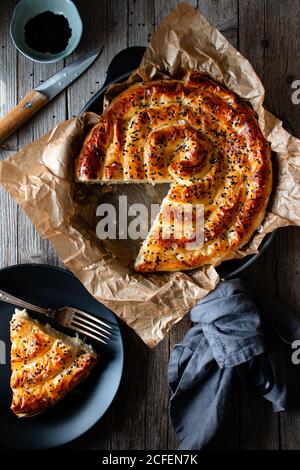 Von oben Ernte kochen hält heißen Auflaufform mit frisch Blätterteig und Servierstück borek auf Teller Stockfoto