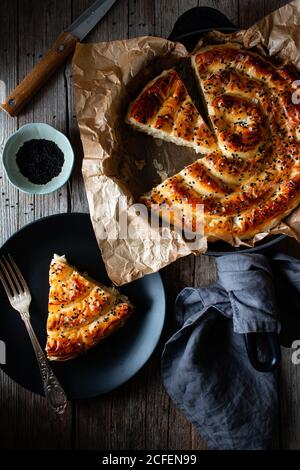 Von oben Ernte kochen hält heißen Auflaufform mit frisch Blätterteig und Servierstück borek auf Teller Stockfoto