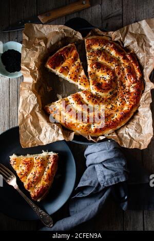 Von oben Ernte kochen hält heißen Auflaufform mit frisch Blätterteig und Servierstück borek auf Teller Stockfoto