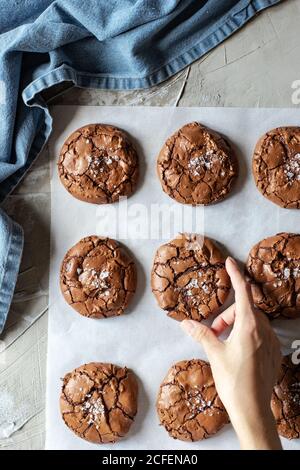 Von oben Zusammensetzung der köstlichen Schokolade Brownie Cookies auf weiß Pergament und blaues Handtuch Stockfoto