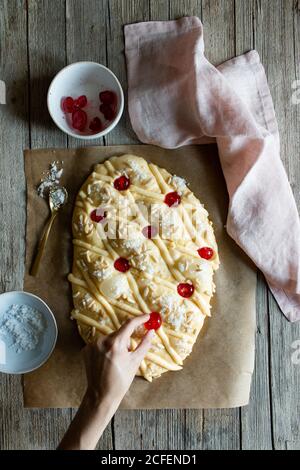 Von oben nicht erkennbare Person Dekoration traditionelle Coca de San Juan Gebäck beim Kochen auf Holztisch in der Küche Stockfoto