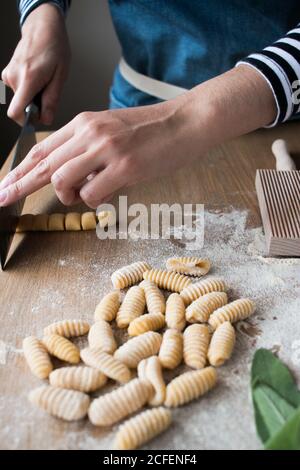 Anonymer weiblicher Schneid-Teig für hausgemachte Gnocchetti Pasta auf dem Tisch In der Küche Stockfoto