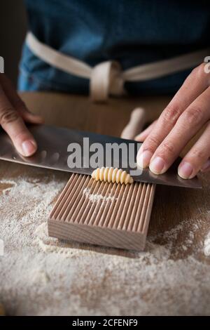 Anonyme weibliche Vorbereitung Teig für hausgemachte Gnocchetti Pasta auf einem Holzwerkzeug im Tisch in der Küche Stockfoto