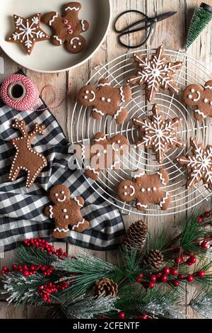 Blick von oben auf traditionelle hausgemachte Lebkuchen mit Glasur auf gelegt Holztisch mit dekorativen Baum Zweig für Weihnachtsfeier vorbereitet Stockfoto