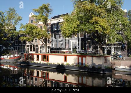 Häuser und Hausboot spiegeln sich im Wasser der Prinsengracht direkt gegenüber dem Anne Frank Haus in Amsterdam, früh am Morgen Stockfoto