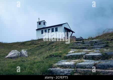 Bezaubernde Landschaft von kleinen weißen Kirche auf der grünen Tal mit steinigen Weg in Österreich Stockfoto
