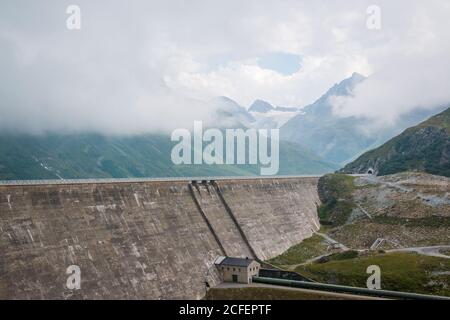 Hochalpenstraße auf großem Damm im Hintergrund mit neblig wolkig Berge in Österreich Stockfoto
