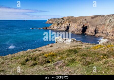 Cornish Coast und Atlantic View in der Nähe von Land’s End vom South West Coast Path mit Pendower Coves, Headland und Distant Longships Lighthouse. Stockfoto