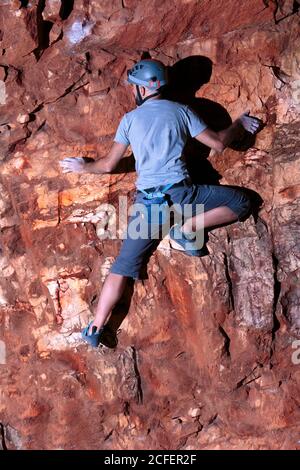 Mutiger hispanischer Bergsteiger, der vorsichtig an einer Felswand balanciert Stockfoto