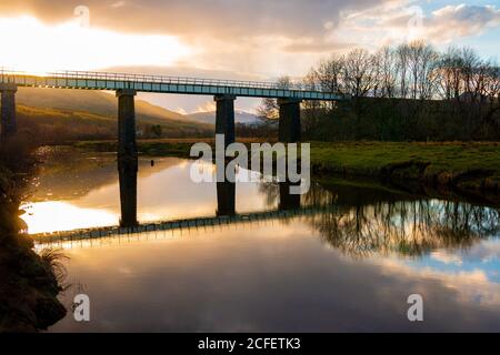 Erstaunliche Landschaft mit alten Brücke überqueren ruhigen Fluss und reflektiert Im Wasser während der Sonnenuntergangszeit im Frühling Abend in schottischen Highlands Stockfoto