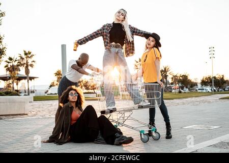 Multirassische Gruppe junger Frauen, die um den Einkaufswagen herum stehen Straße Stockfoto