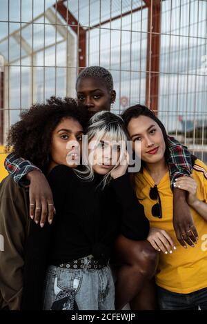 Verschiedene Gruppe von lächelnden Frauen umarmt zusammen auf dem Rasen Stockfoto