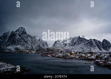 Von oben am Stadthafen gegen verschneite Bergrücken an Horizont bei bewölktem Wetter in Norwegen Stockfoto