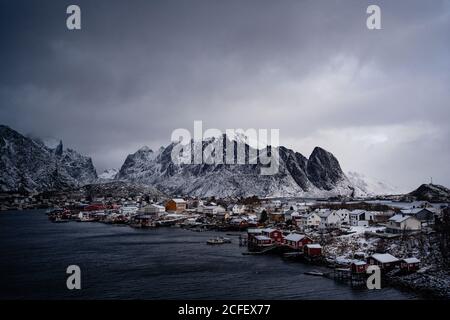 Von oben am Stadthafen gegen verschneite Bergrücken an Horizont bei bewölktem Wetter in Norwegen Stockfoto