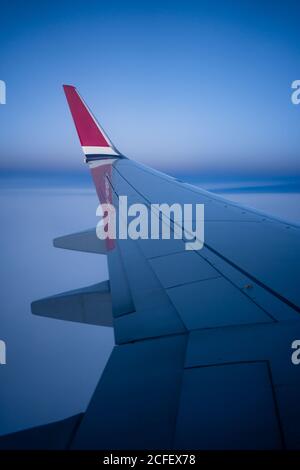 Durch das Fenster Blick auf Flügel der modernen Flugzeug fliegen über Wolken in dunkler Nacht Stockfoto