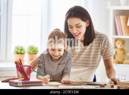 Frohe Familie. Mutter und Tochter lernen zu schreiben. Erwachsene Frau lehrt Kind das Alphabet. Stockfoto