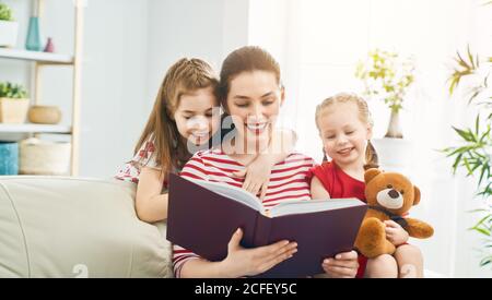 Glücklich liebende Familie. Hübsche junge Mutter Lesung ein Buch zu ihren Töchtern Stockfoto