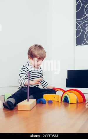 Blonde niedlichen Jungen spielen mit waldorf Regenbogen Puzzle Stockfoto