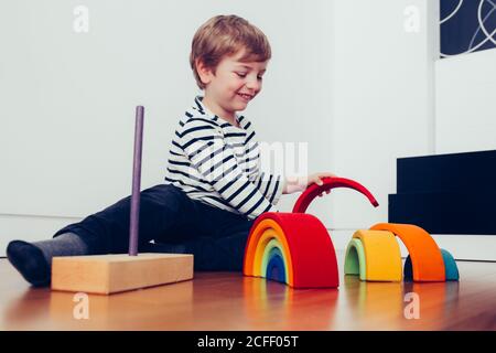 Blonde niedlichen Jungen spielen mit waldorf Regenbogen Puzzle Stockfoto