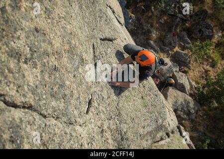 Von oben junge Abenteurer klettern Berg trägt Sicherheitsgeschirr gegen Malerische Landschaft Stockfoto