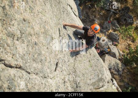 Von oben junge Abenteurer klettern Berg trägt Sicherheitsgeschirr gegen Malerische Landschaft Stockfoto