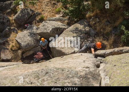 Von oben junge Abenteurer klettern Berg trägt Sicherheitsgeschirr gegen Malerische Landschaft Stockfoto