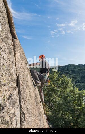 Mann klettert in der Natur mit Kletterausrüstung auf einen Felsen Stockfoto