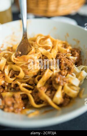 Von oben Nahaufnahme von leckeren hausgemachten Pasta mit traditionellen Bolognese Sauce in weißem Teller mit Gabel serviert Stockfoto