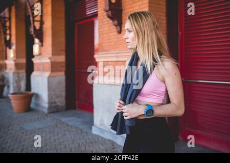 Junge blonde kaukasische Frau, die sich von einer Laufsitzung mit einem Handtuch in den Hals gewickelt ausruhte Stockfoto
