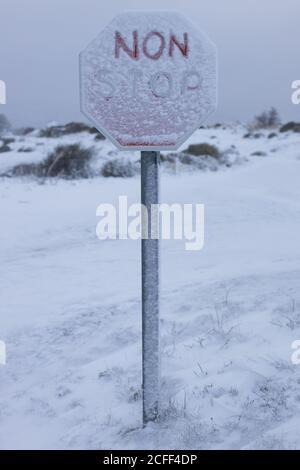 Schneebedecktes Schild Halt auf weißem abgelegenen Gelände des Hügels Gegen grau düsteren Himmel Stockfoto