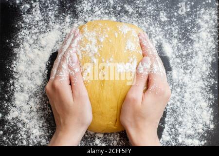 Teig mit weiblichen Händen auf schwarzem Hintergrund machen Stockfoto